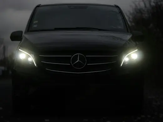 Black Mercedes-Benz executive van with headlights on