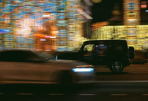 Black SUV gliding past city lights at night