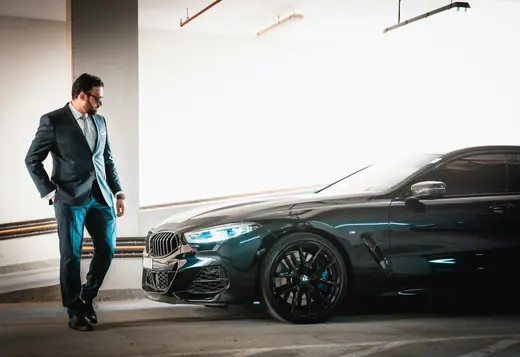 Executive in a suit walking to a black luxury car